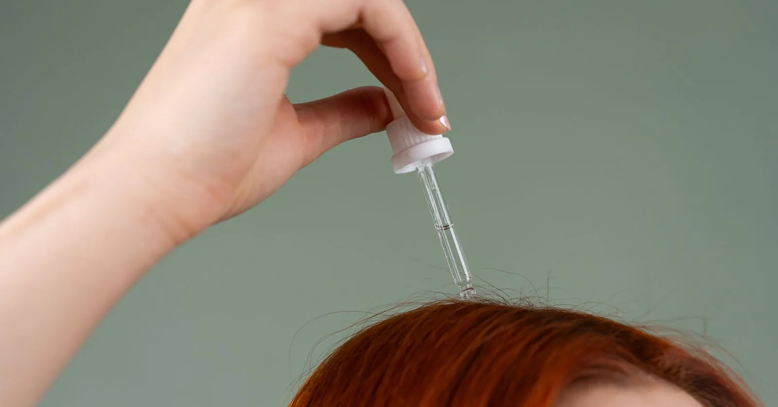 Hand träufelt Haarserum mit einer Pipette auf die Kopfhaut